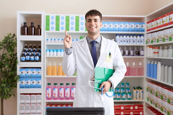 Молодой Латиноамериканец Работающий Аптеке Держит Стетоскоп Улыбаясь Счастливо Указывая Рукой — стоковое фото
