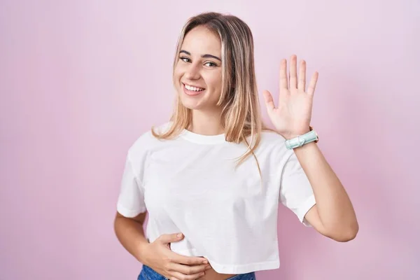 Young Blonde Woman Standing Pink Background Waiving Saying Hello Happy — ストック写真