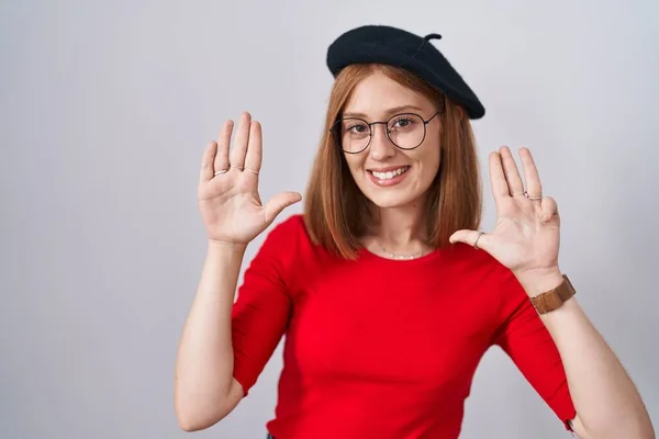 年轻的红头发女人站在那里 戴着眼镜 头戴贝雷帽 用9号手指显示和指尖 面带微笑 自信而快乐 — 图库照片