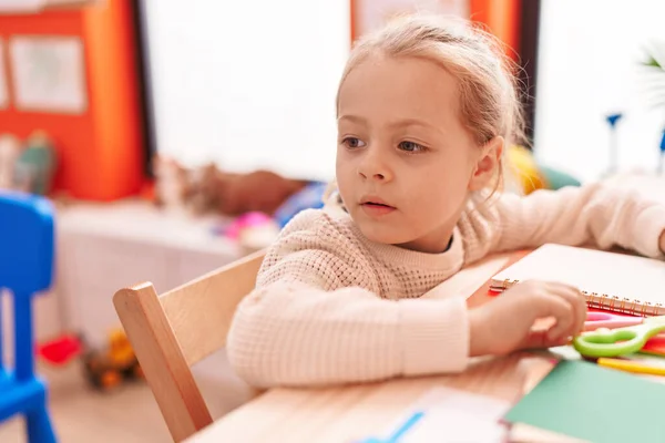 Adorable Blonde Girl Preschool Student Sitting Table Relaxed Expression Kindergarten — Foto Stock