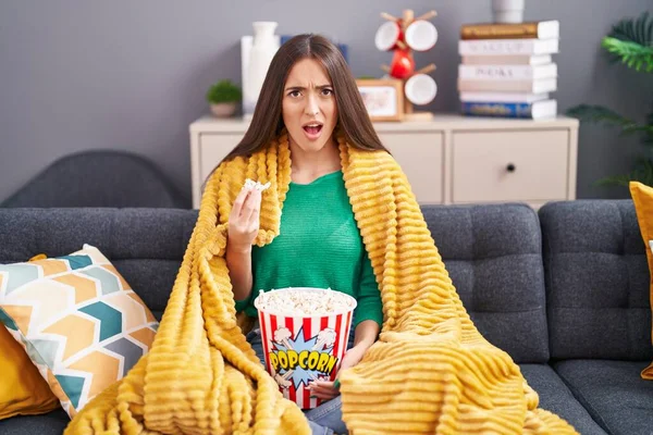 Young Hispanic Woman Eating Snack Sitting Sofa Home Shock Face — Stock Photo, Image