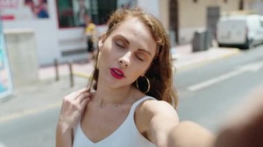 Genç ve güzel İspanyol kadın gülümsüyor. Kendine güvenen. Sokakta kamerayla selfie çekiyor.