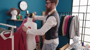 Genç kızıl saçlı terzi elbise fabrikasında manikin giyiyor.