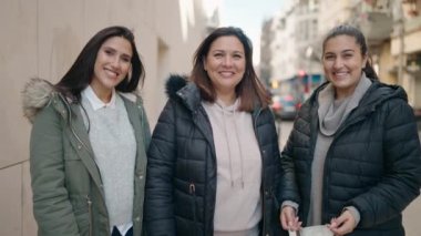 Anne ve kızları sokakta duran tıbbi maske takıyor.