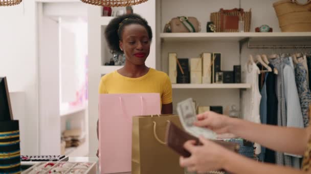 アフリカ系アメリカ人女性ショップのアシスタントや衣料品店で服を支払う顧客 — ストック動画