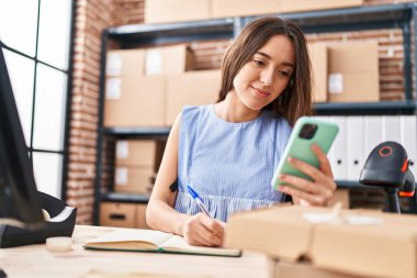 Genç, güzel İspanyol kadın, iş adamı. Ofisteki defterde akıllı telefon yazıları kullanıyor.