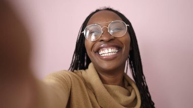 African woman taking selfie smiling over isolated pink background