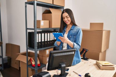 Genç, güzel, İspanyol bir kadın. İş kadını. Ofiste dokunmatik ped kullanıyor.