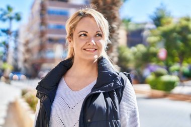 Young blonde woman smiling confident looking to the side at park