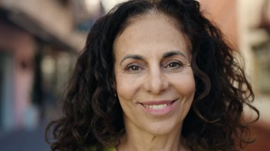 Middle age hispanic woman smiling confident at street