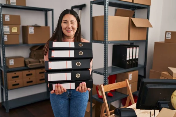 Young Latin Woman Working Small Business Ecommerce Holding Folders Winking — Stock Photo, Image