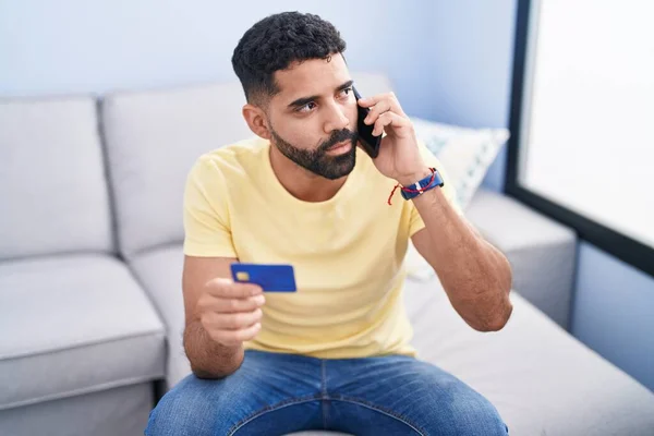 Hombre Árabe Joven Hablando Teléfono Inteligente Tarjeta Crédito Sentado Sofá — Foto de Stock