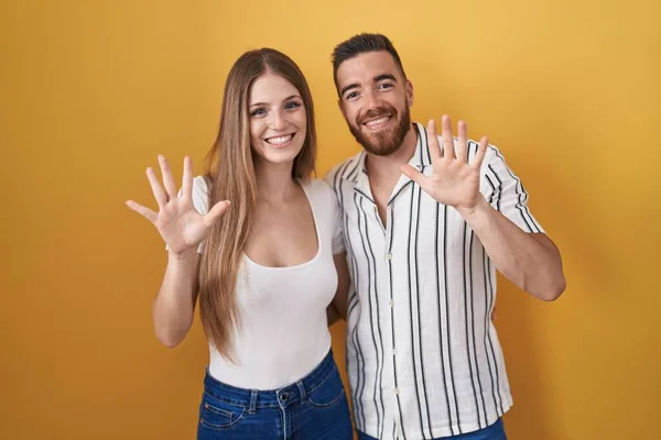 Young Couple Standing Yellow Background Showing Pointing Fingers Number Ten — Stockfoto