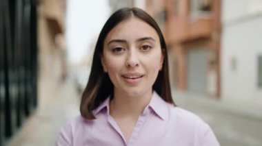 Young hispanic woman smiling confident doing photo gesture with hands at street