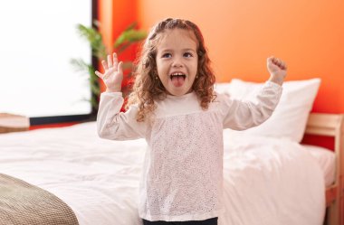 Sevimli sarışın bebek gülümsüyor. Yatak odasında kendine güvenerek dans ediyor.