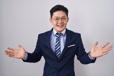 Young asian man wearing business suit and tie celebrating crazy and amazed for success with arms raised and open eyes screaming excited. winner concept 