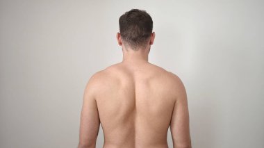 Young caucasian man standing backwards shirtless over isolated white background