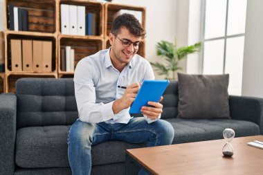 Psikoloji kliniğinde dokunmatik pedini kullanarak gülümseyen genç İspanyol psikolog.