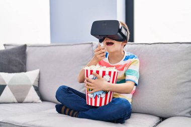 Blond child watching movie by virtual reality glasses at home