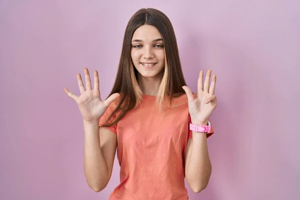 少女站在粉红的背景上 用9号手指指指指点点 面带微笑 自信而快乐 — 图库照片