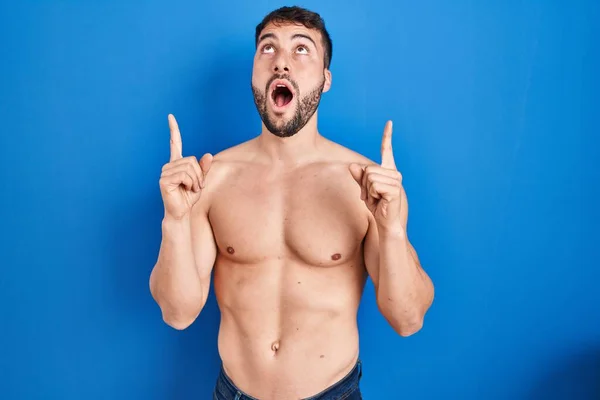 Handsome Hispanic Man Standing Shirtless Amazed Surprised Looking Pointing Fingers — Zdjęcie stockowe