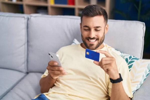 Joven Hombre Hispano Usando Teléfono Inteligente Tarjeta Crédito Sentado Sofá — Foto de Stock