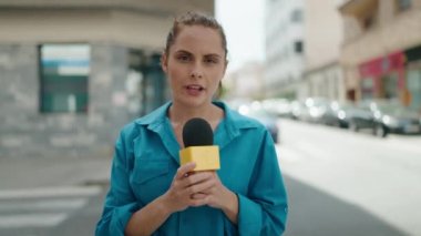 Young woman reporter working using microphone at street