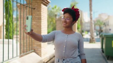 Afro-Amerikalı kadın sokakta akıllı telefon kullanarak kendine güveniyor.