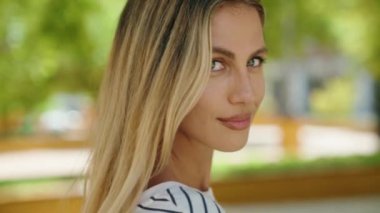 Parkta kendinden emin gülümseyen genç sarışın kadın.