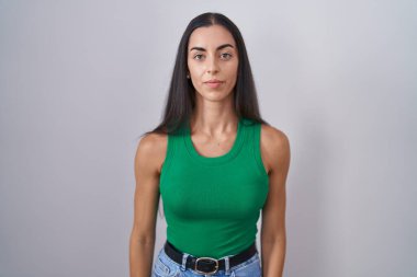 Young woman standing over isolated background relaxed with serious expression on face. simple and natural looking at the camera. 