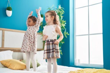 Two kids smiling confident dancing on bed at bedroom