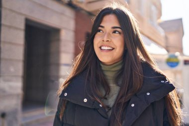 Young beautiful hispanic woman smiling confident looking to the side at street