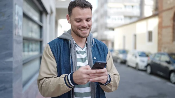若い白人男性が路上でスマートフォンを使って笑っています — ストック写真