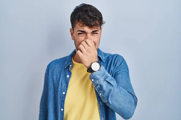 Young Hispanic Man Standing Blue Background Smelling Something Stinky Disgusting — Stockfoto
