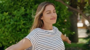 Parkta klasik kamera kullanan, kendine güvenen genç sarışın kadın.