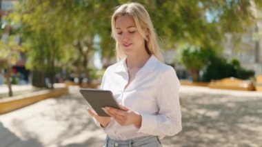 Parkta dokunmatik ped kullanan kendine güvenen genç sarışın kadın.