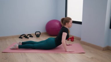 Genç sarışın kadın spor merkezinde yoga eğitimi alıyor.