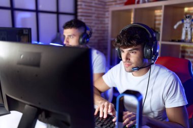 Oyun odasında bilgisayar kullanarak video oyunu oynayan iki İspanyol adam.