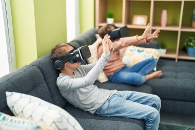 Evde sanal gerçeklik gözlüğü kullanarak video oyunu oynayan iki çocuk.