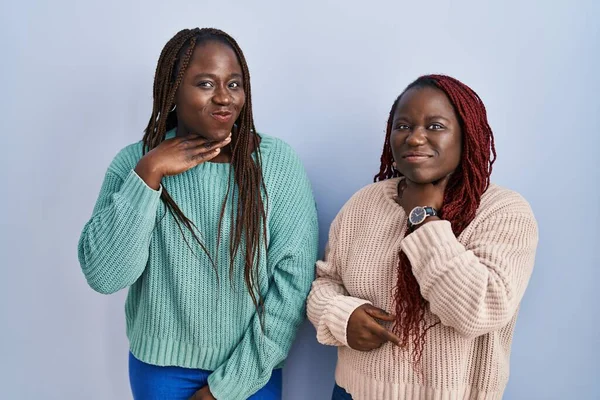 Dos Mujeres Africanas Pie Sobre Fondo Azul Cortando Garganta Con —  Fotos de Stock