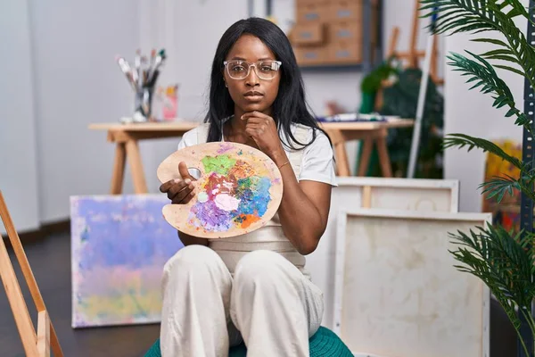 African Young Woman Holding Painter Palette Serious Face Thinking Question — Stok fotoğraf