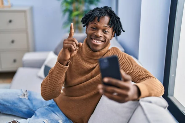 Młody Afrykanin Dredami Korzystający Smartfona Wykonujący Połączenie Wideo Uśmiechnięty Pomysłem — Zdjęcie stockowe