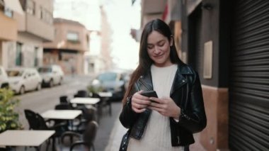 Sokakta akıllı telefon kullanan, kendine güvenen genç İspanyol kadın.