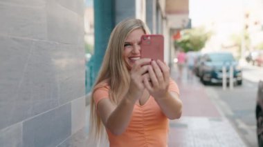 Kendine güvenen genç sarışın kadın akıllı telefondan fotoğraf çekiyor.