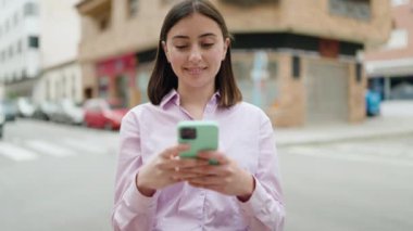 Sokakta akıllı telefon kullanan, kendine güvenen genç İspanyol kadın.