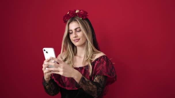 Молода Блондинка Використовує Смартфон Вечіркою Хеллоуїн Над Ізольованим Червоним Тлом — стокове відео