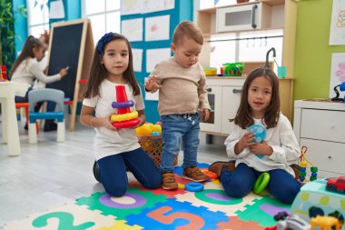 Group of kids playing with hoops toys sitting on floor at kindergarten