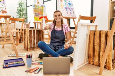 Sanat stüdyosunda kendine güvenen, gülümseyen genç bir kadın.