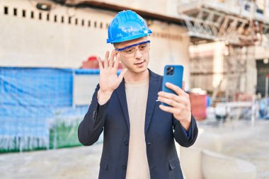 Young hispanic man architect having video call at street