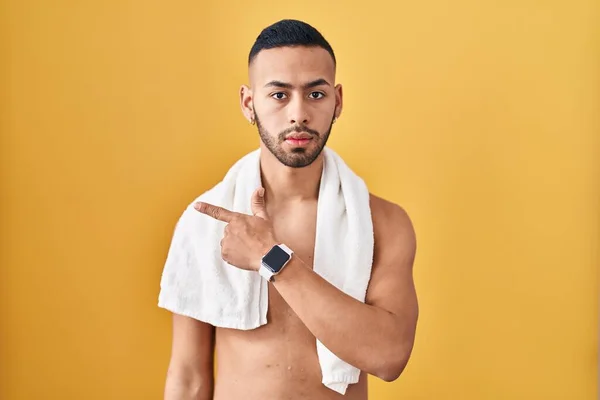 Mladý Hispánec Stojící Bez Košile Ručníkem Ukazujícím Ukazováčkem Stranu Reklamou — Stock fotografie